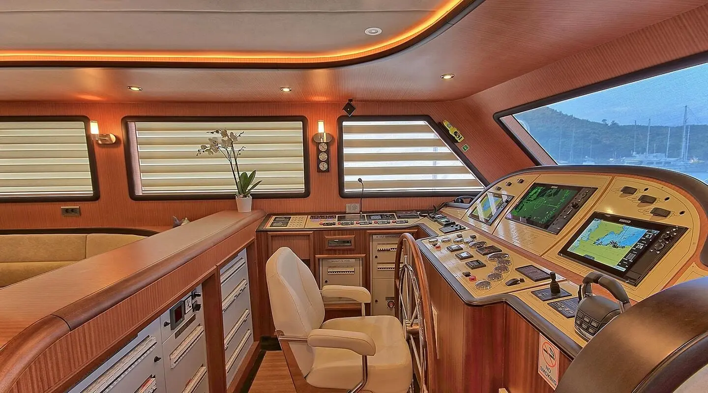 Interior of a yacht at sunset with wooden cabinetry, seating, and helm area