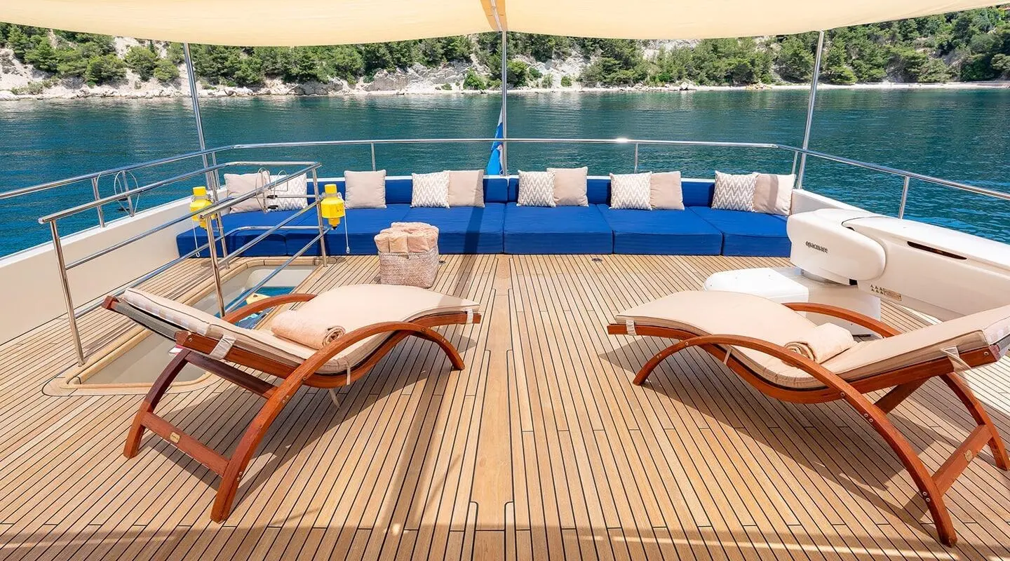 Grace yacht sun loungers on teak deck with blue railing and water in background