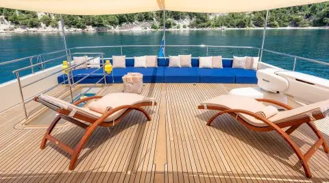 Grace yacht sun loungers on teak deck with blue railing and water in background