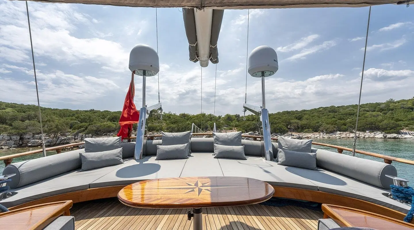 View from yacht deck with chairs, table, and calm water at sunset