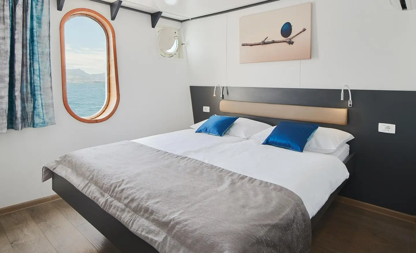 Lupus Mare motor yacht interior: double cabin with bed, pillows, and window