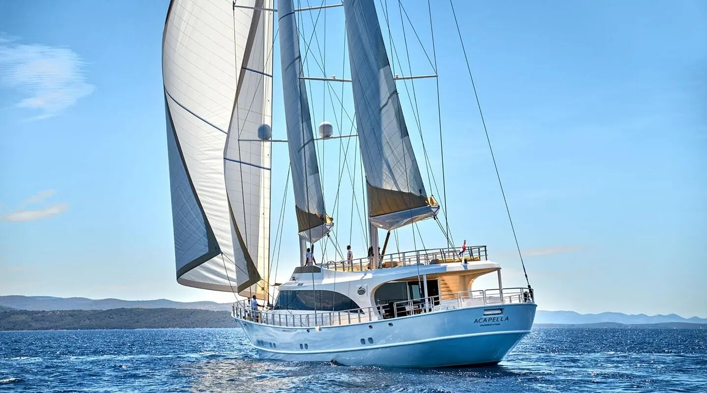 Acapella motor yacht with sails on the blue sea under windy conditions