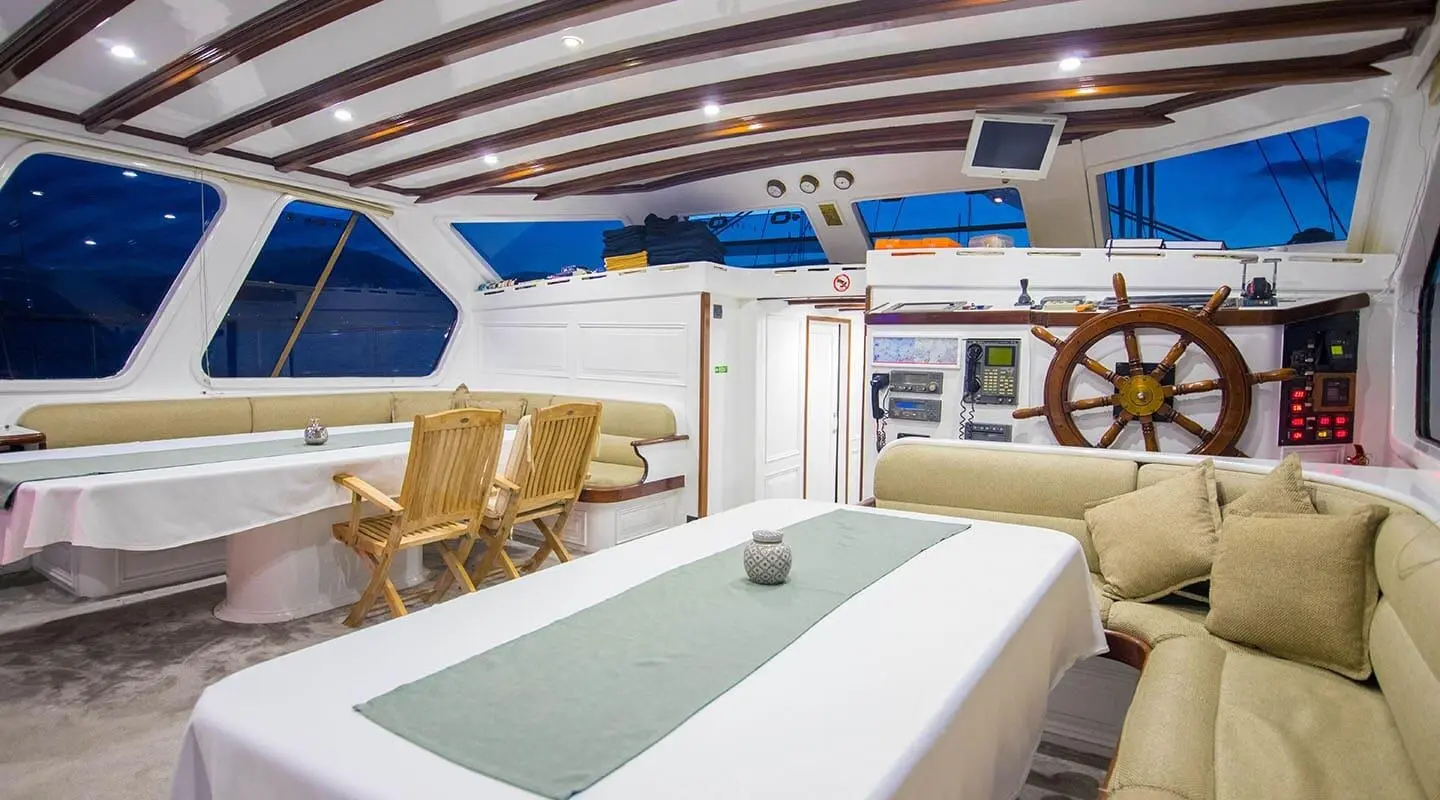Interior deck seating and table on Grande Mare yacht, helm visible
