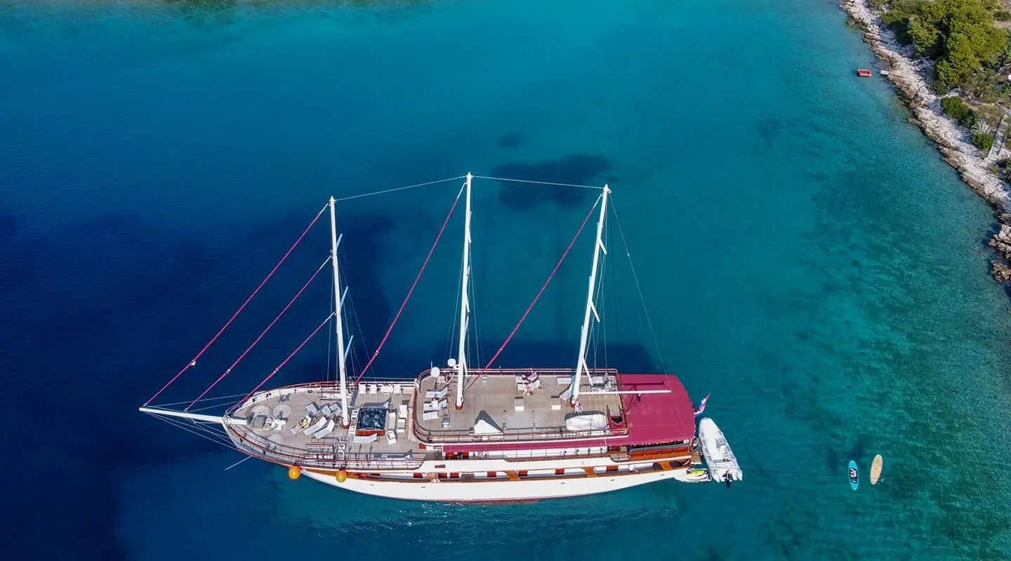 Amorena yacht viewed from above, red deck and white hull on calm water
