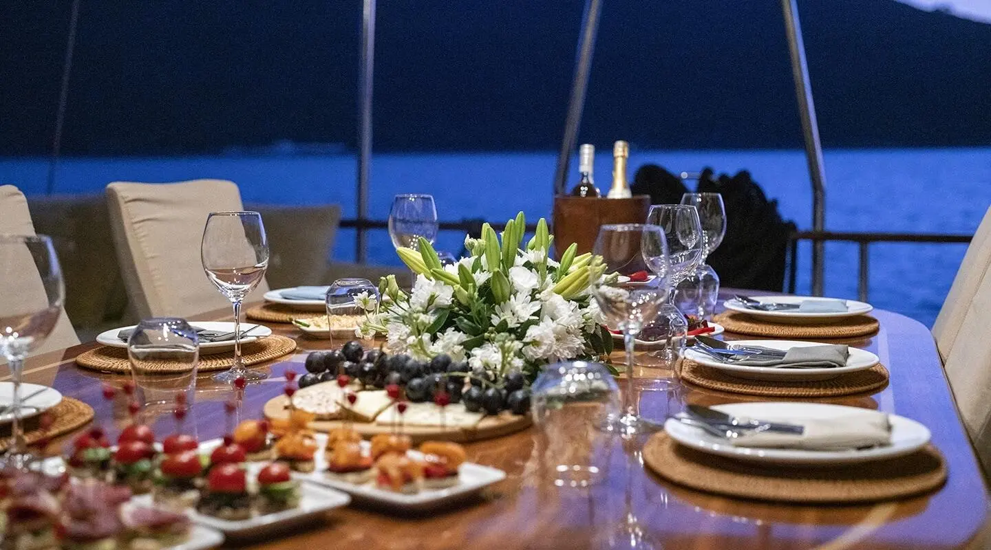 Queen Of Sea yacht table setting at sunset with flowers and wine glasses
