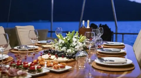 Queen Of Sea yacht table setting at sunset with flowers and wine glasses