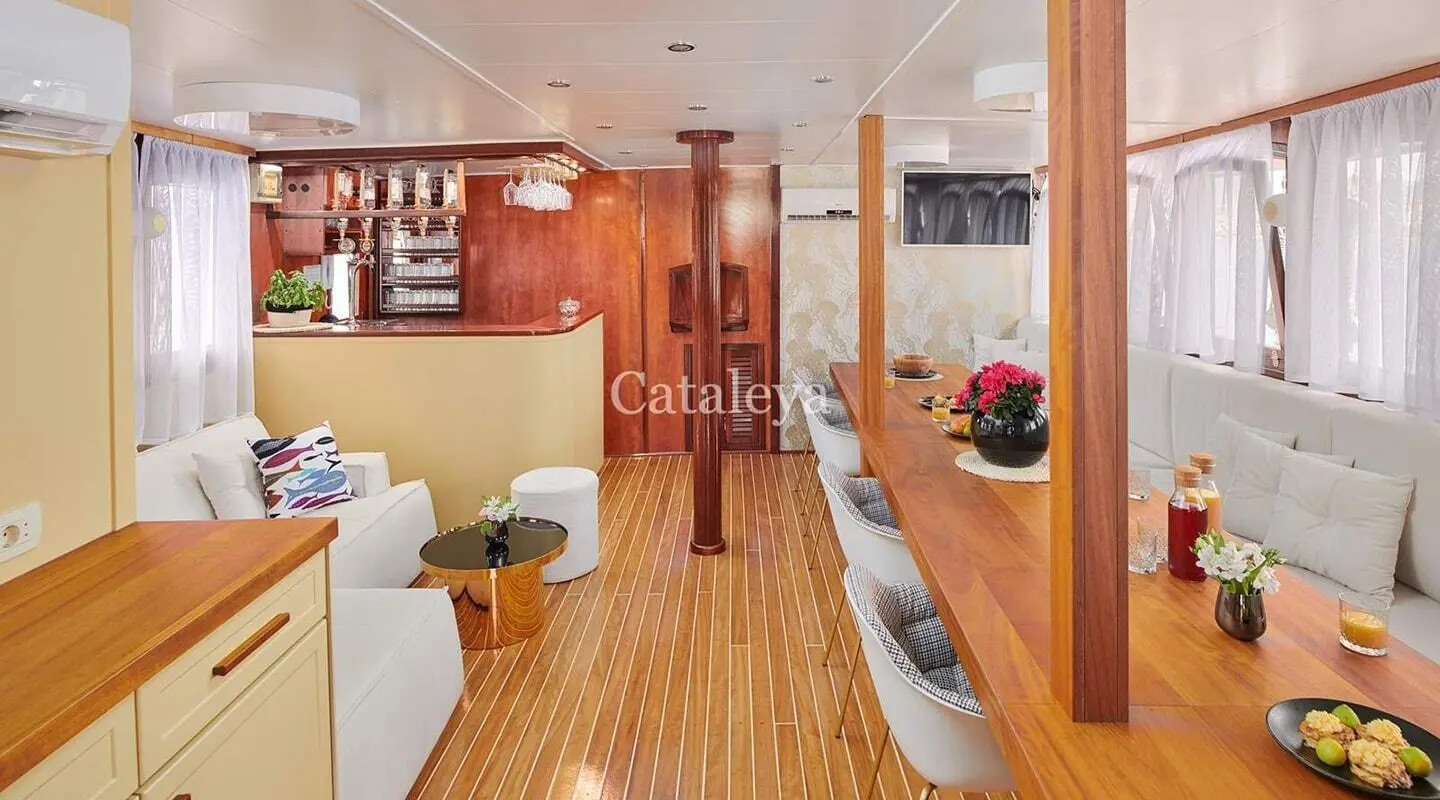 Yacht interior with wooden flooring, seating, and shelves, name Cataleya visible
