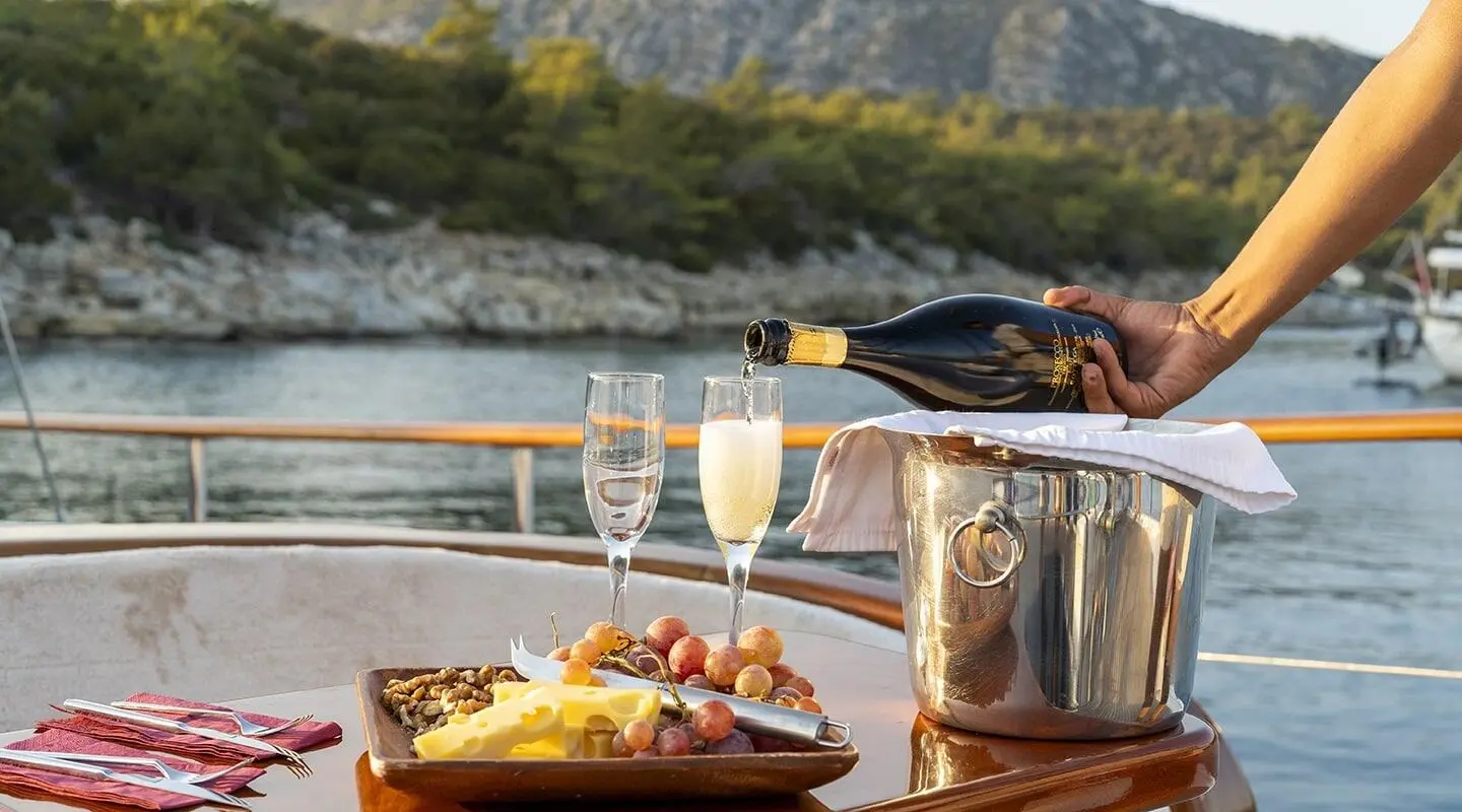 Yacht Artemis scene with champagne glass and appetizers on deck, gulet cruise