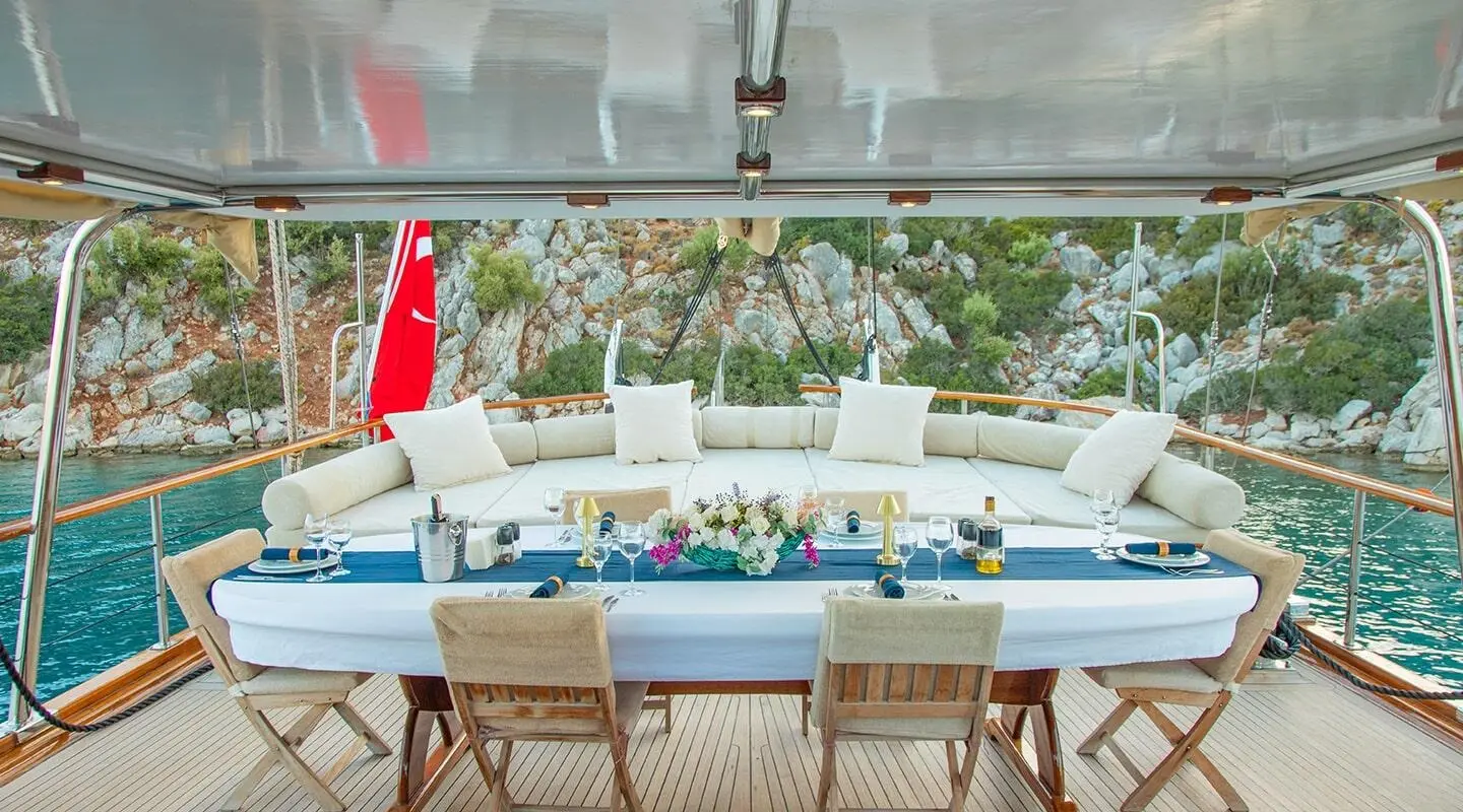 Derin Deniz luxury gulet: outdoor dining area on deck with chairs and table set, sunset glow