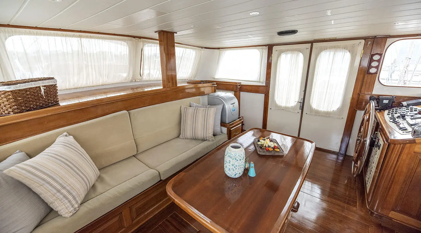 Wooden interior of a yacht saloon with large windows and seating