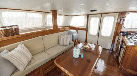 Wooden interior of a yacht saloon with large windows and seating