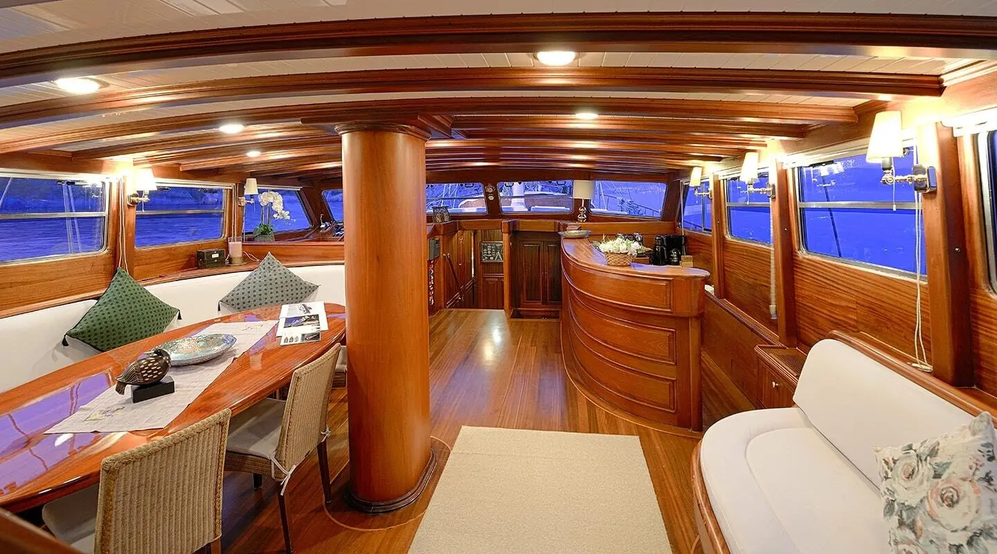 Luxurious yacht Ecce Navigo's sunlit interior with wood paneling and seating
