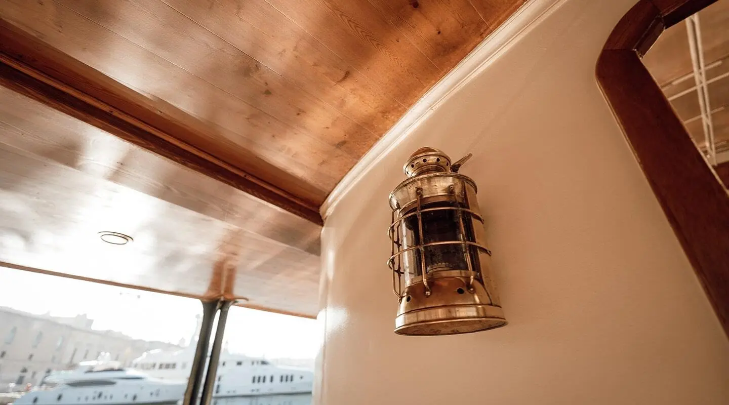 Interior view of Seagull II yacht with a brass lantern mounted on wood panel wall
