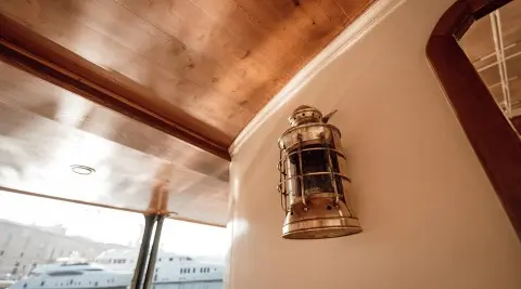 Interior view of Seagull II yacht with a brass lantern mounted on wood panel wall