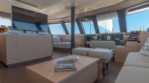 Luxurious yacht saloon interior with TV, seating, and control helm at the background