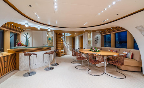 Serenity yacht interior: stylish bar area and round dining table on a luxury deck