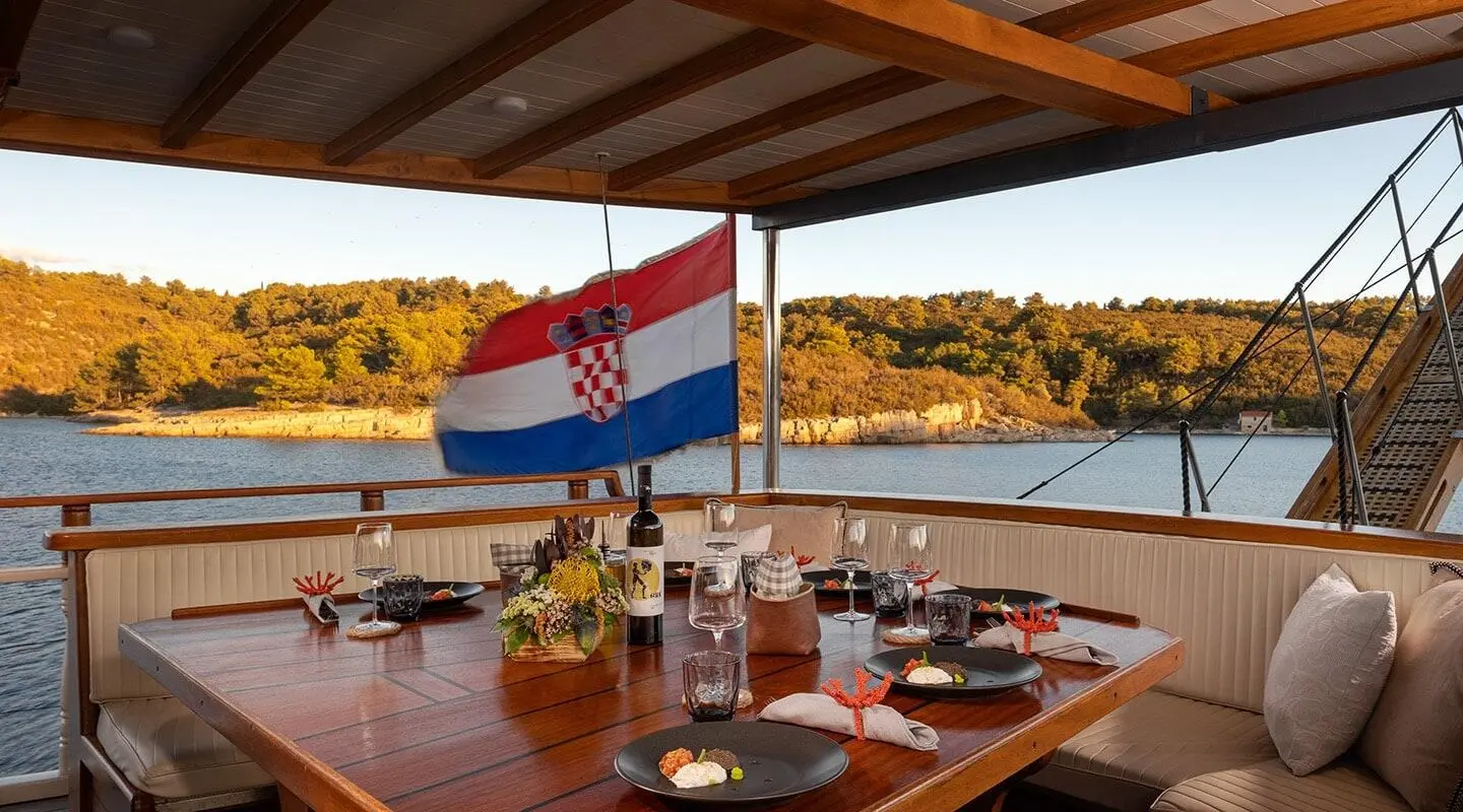 Dining on a luxury Gulet Aborda with sea view at sunset, Turkish flag