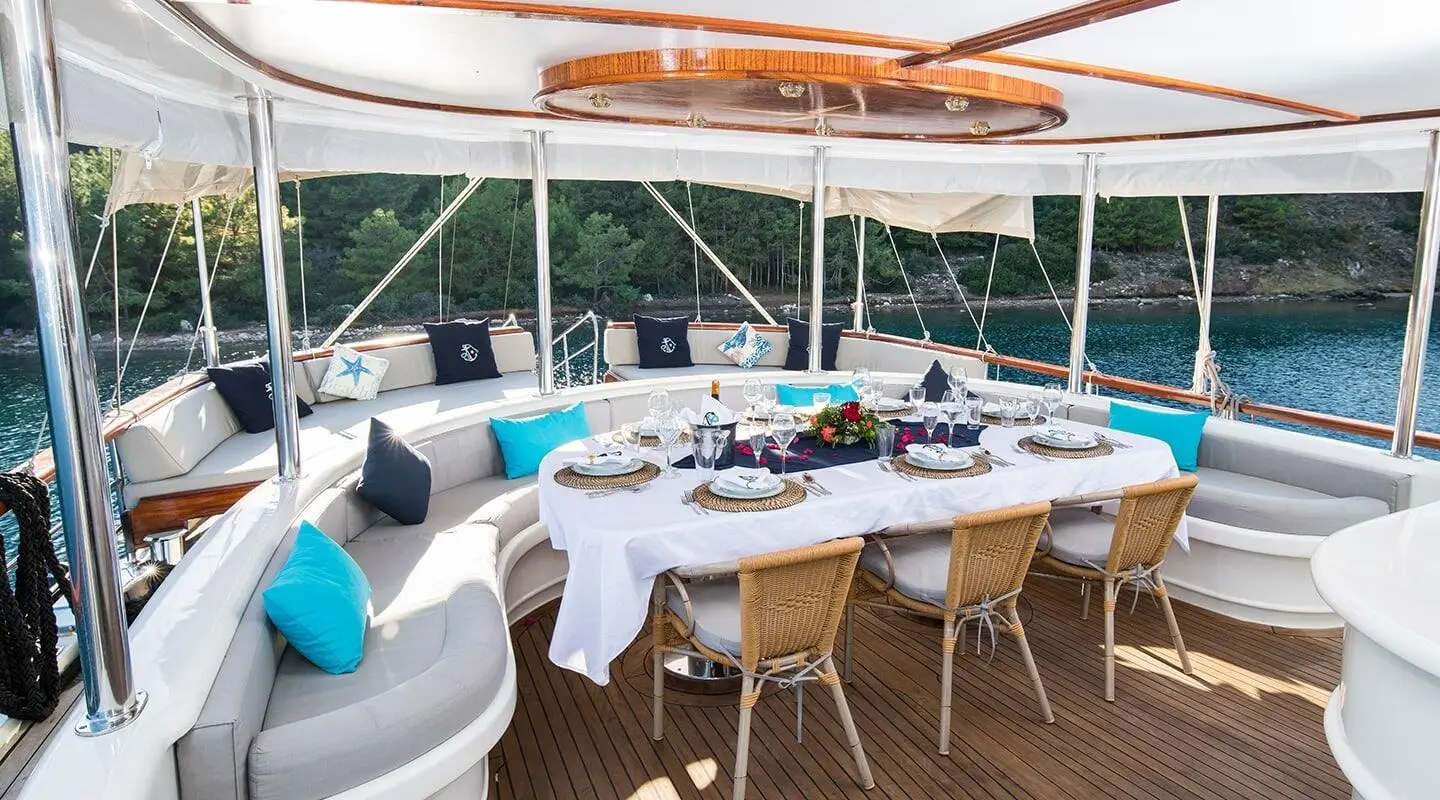 Vista Mare yacht charter: sunlit aft dining on deck with table set and chairs