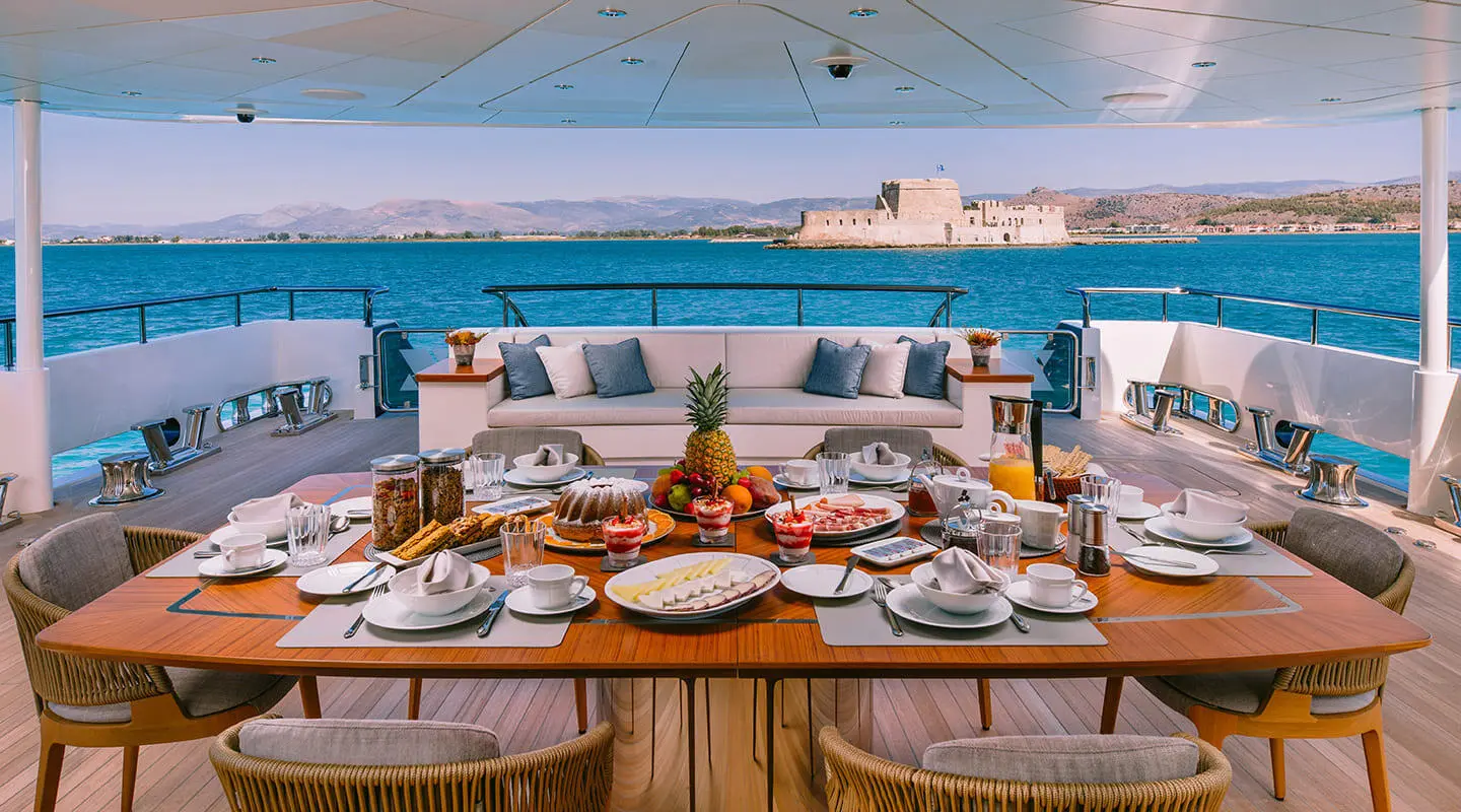 Xana yacht main deck aft with dining setup overlooking blue sea