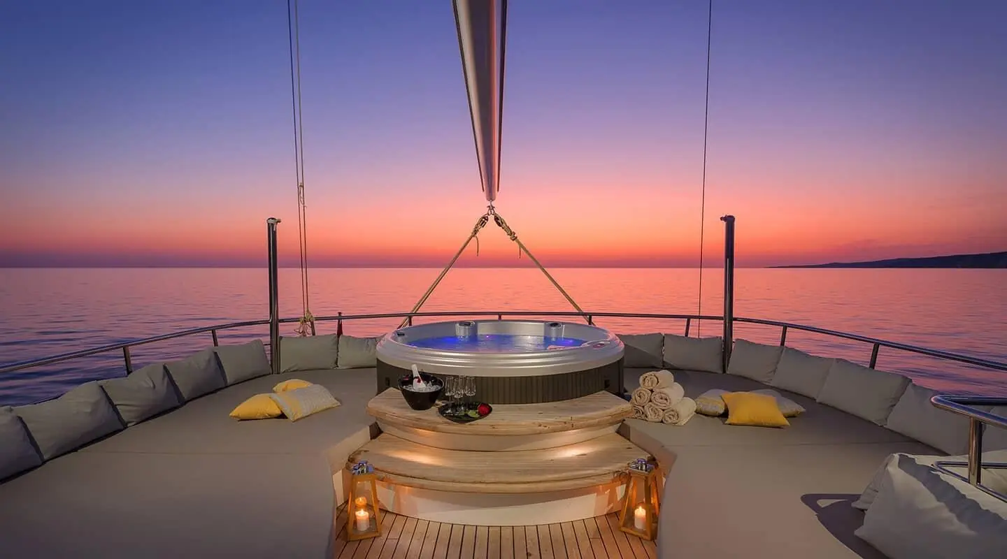 Lady Gita yacht sundeck at sunset with spa tub and plush seating