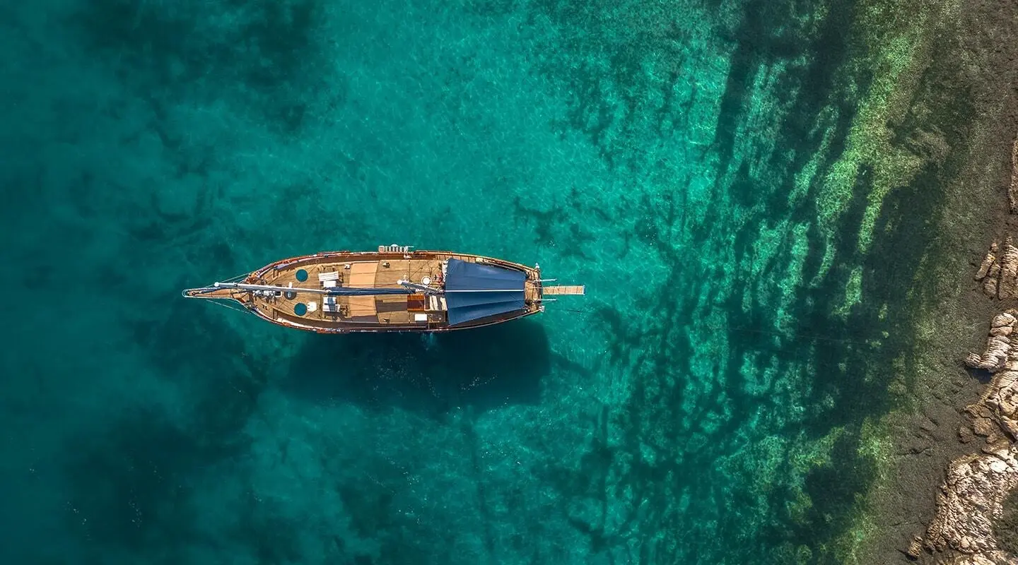 Top-down view of a wooden gulet yacht on turquoise water