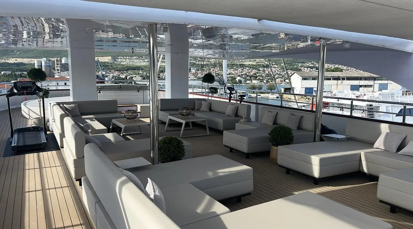 Yacht Melody sun deck with seating area and lounge chairs overlooking calm marina