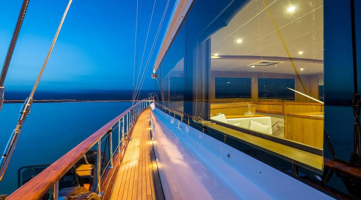 Yacht named Happy Days at dusk with sleek railings and warm lighting along deck