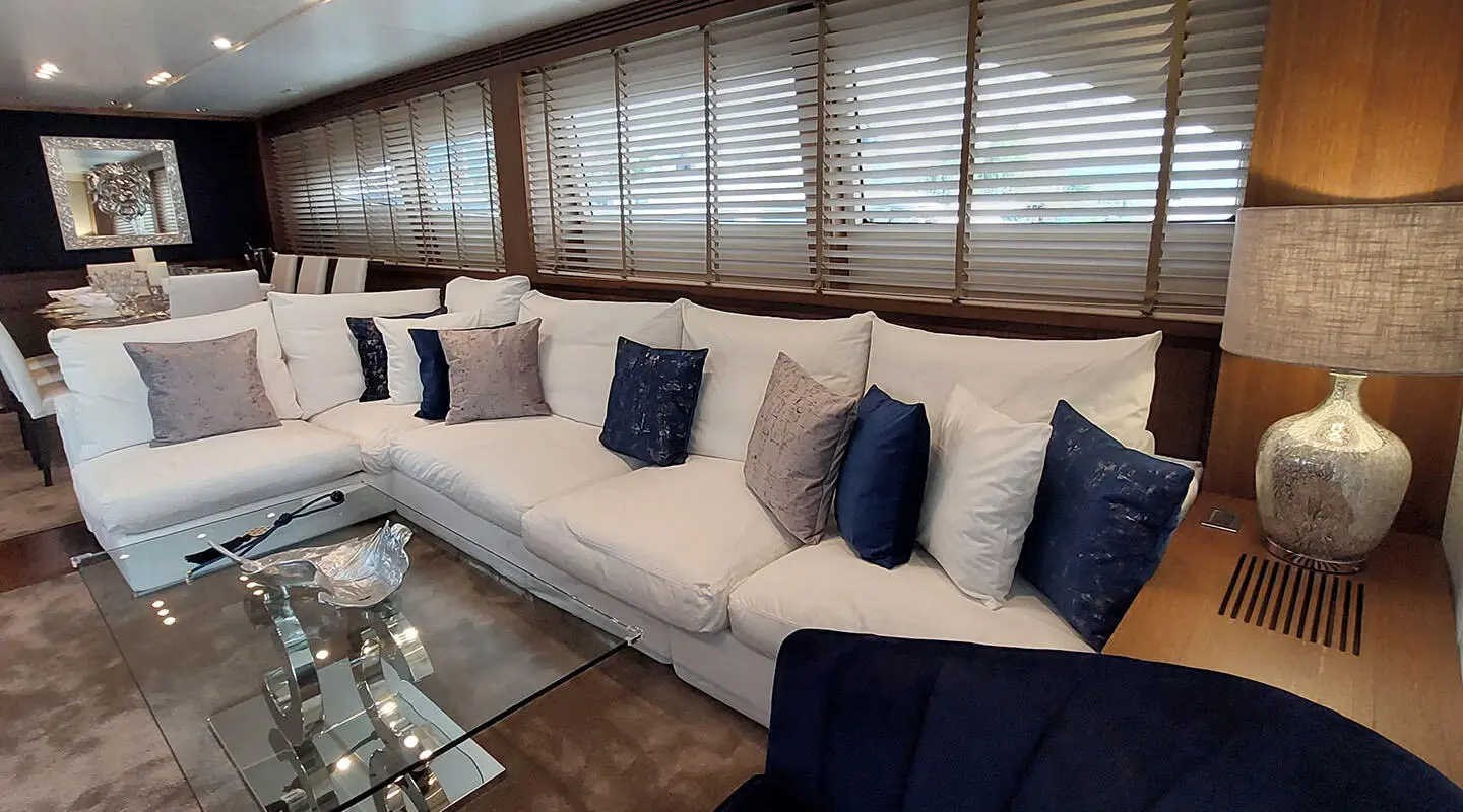 Miraval yacht interior with a long beige sectional couch and blue throw pillows