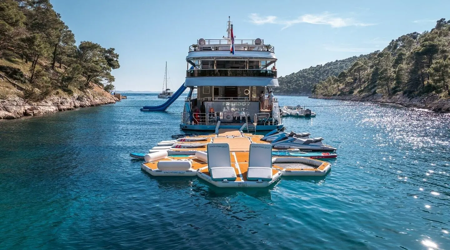 Yacht Freedom anchored in blue harbor with a small inflatable dinghy nearby
