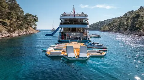 Yacht Freedom anchored in blue harbor with a small inflatable dinghy nearby