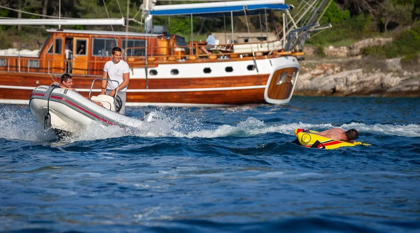Andi Star yacht sailing in blue sea with sunlit wooden hull and passengers