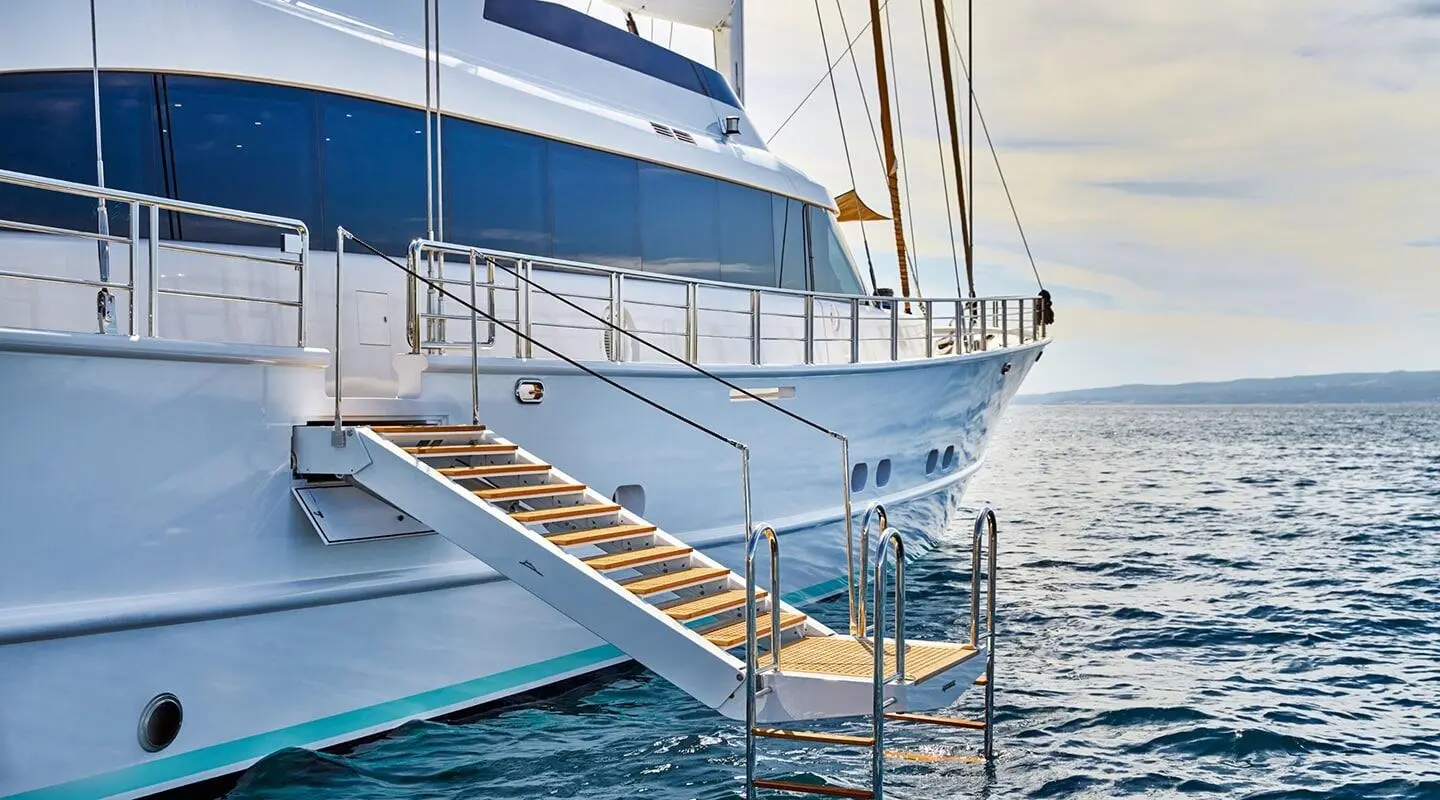 Closeup of Acapella yacht hull and gangway over blue water