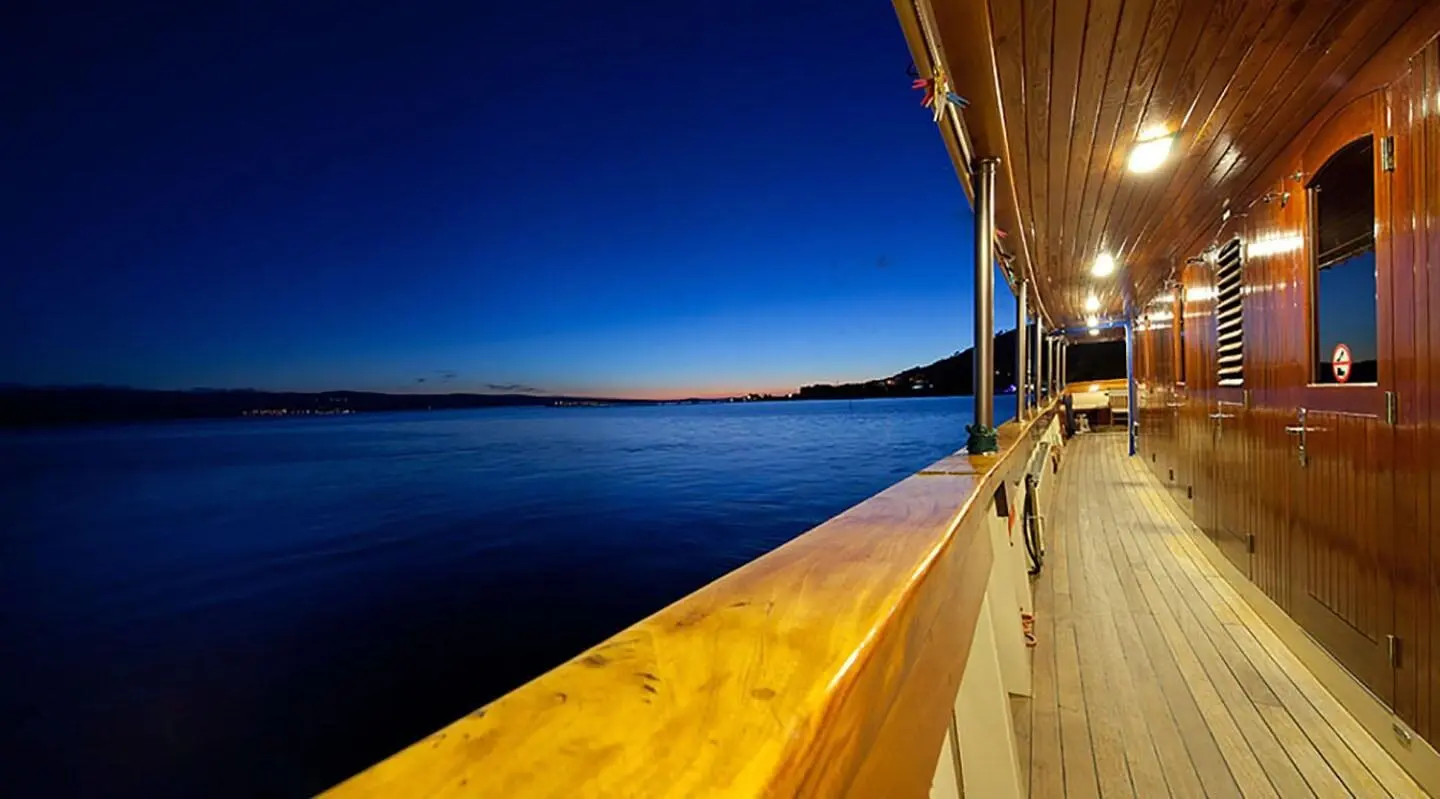 Sunlit wooden yacht deck with calm sea and blue sky at sunset