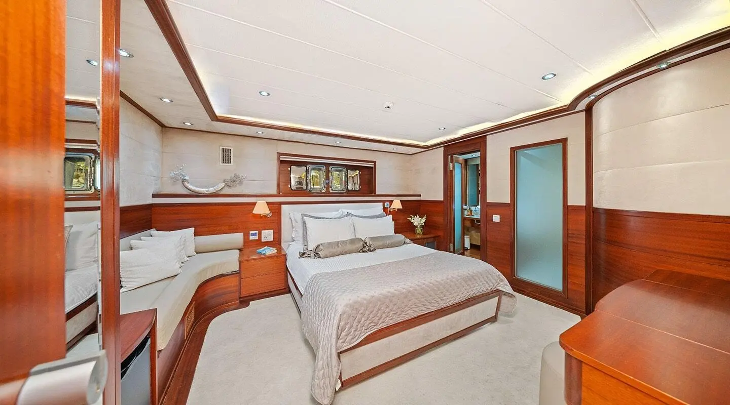 Interior shot of Alessandro I yacht: two double beds, wood panels, seating area