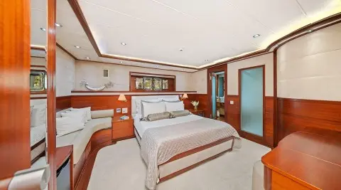 Interior shot of Alessandro I yacht: two double beds, wood panels, seating area