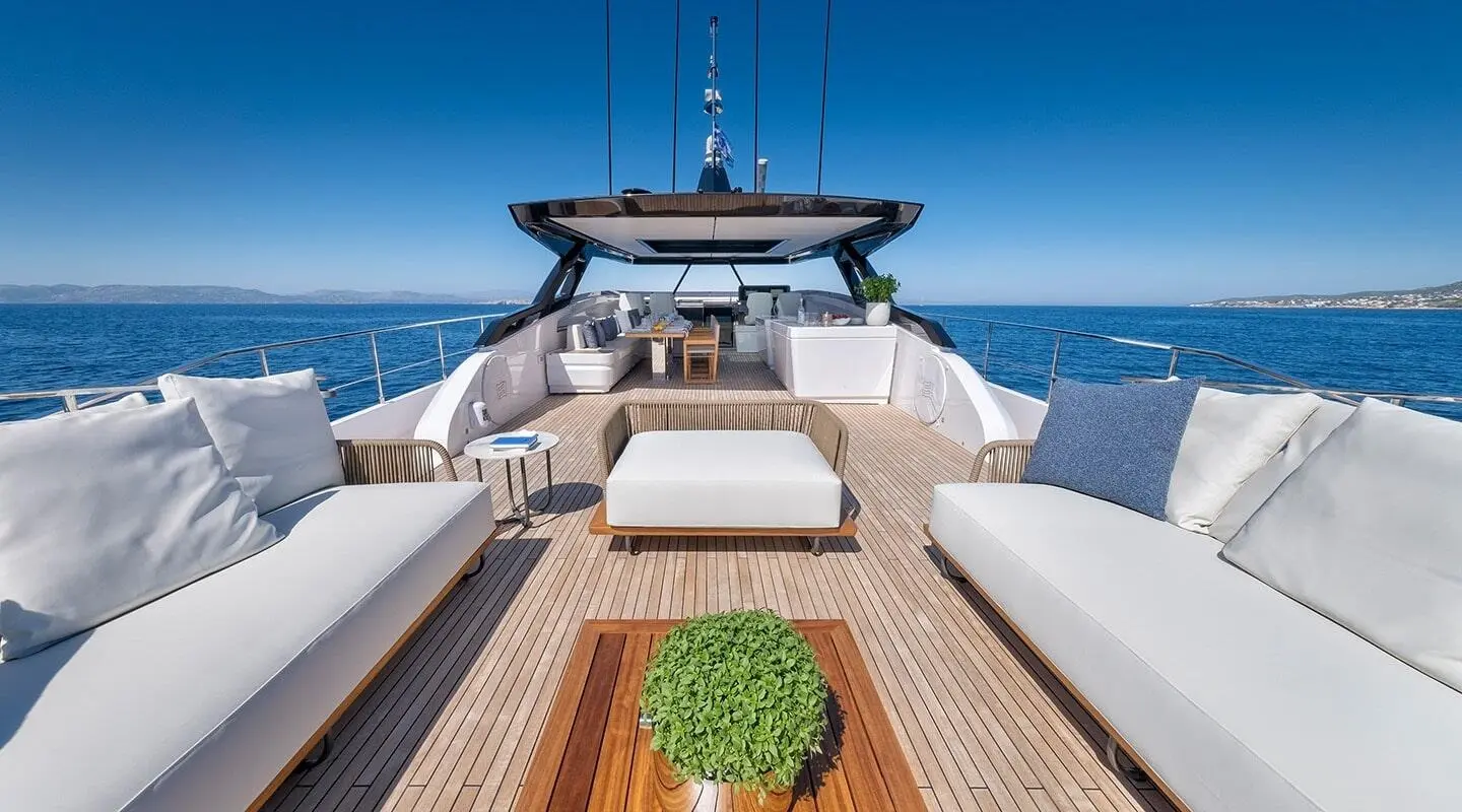 Spica yacht deck view with white seating, wooden planks, and blue sea beyond