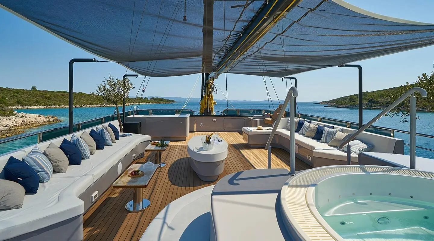 Luxury yacht Rara Avis deck at sunset with seating, stairs, and blue ocean view