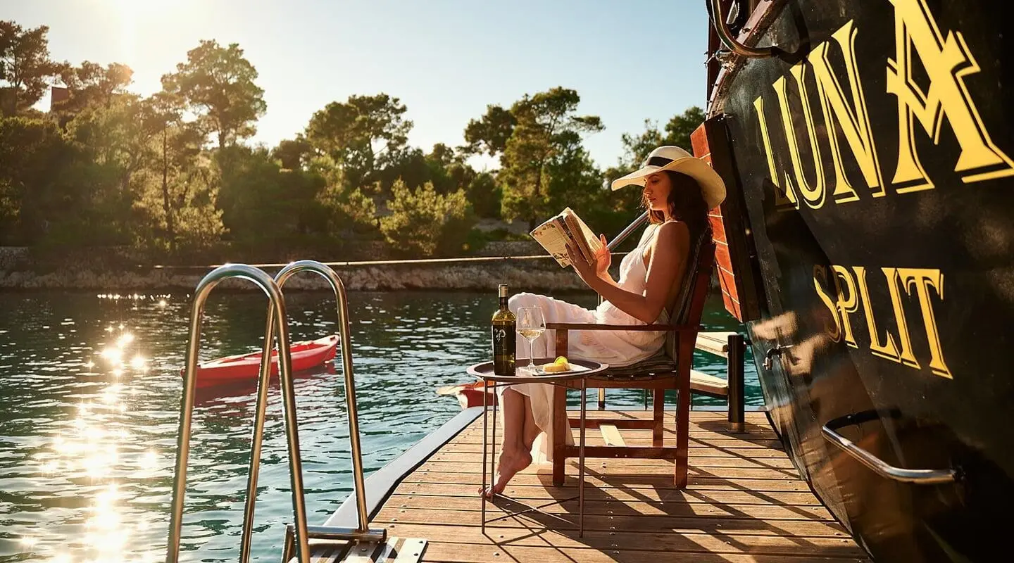 Yacht Luna stern deck with seating, ladder, and calm pool water surface