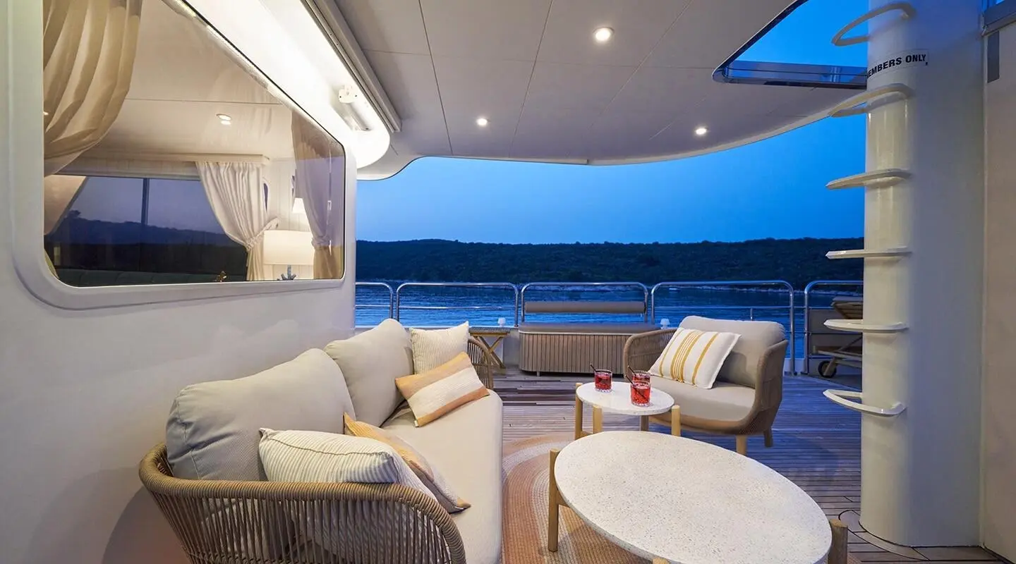 La Perla yacht deck aft seating area with wicker chairs and coffee table at sunset