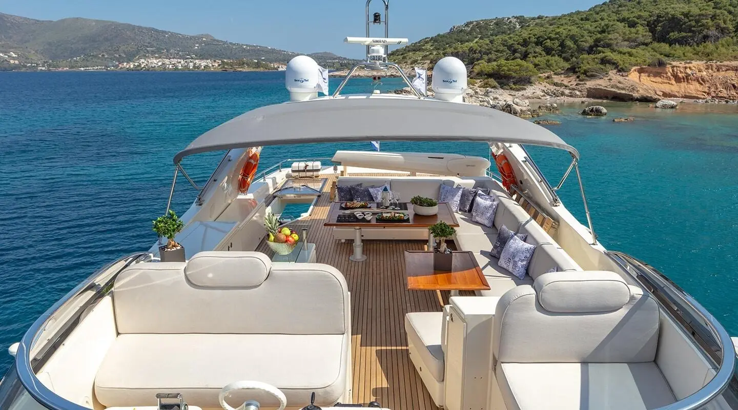 Divine yacht deck lounge with seating, helm, and ocean view at sunset
