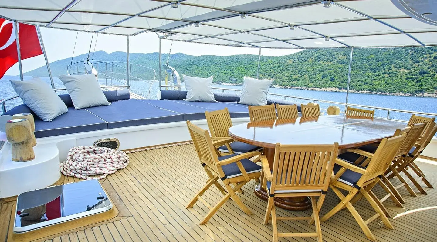 Bella Mare luxury yacht deck with wooden chairs, shaded canopy, and blue sea view