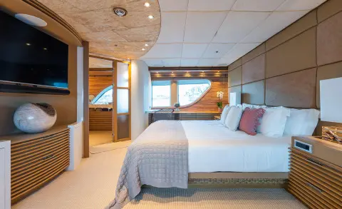 Serenity luxury yacht interior with a bed, blue accent pillows, and wooden cabinetry