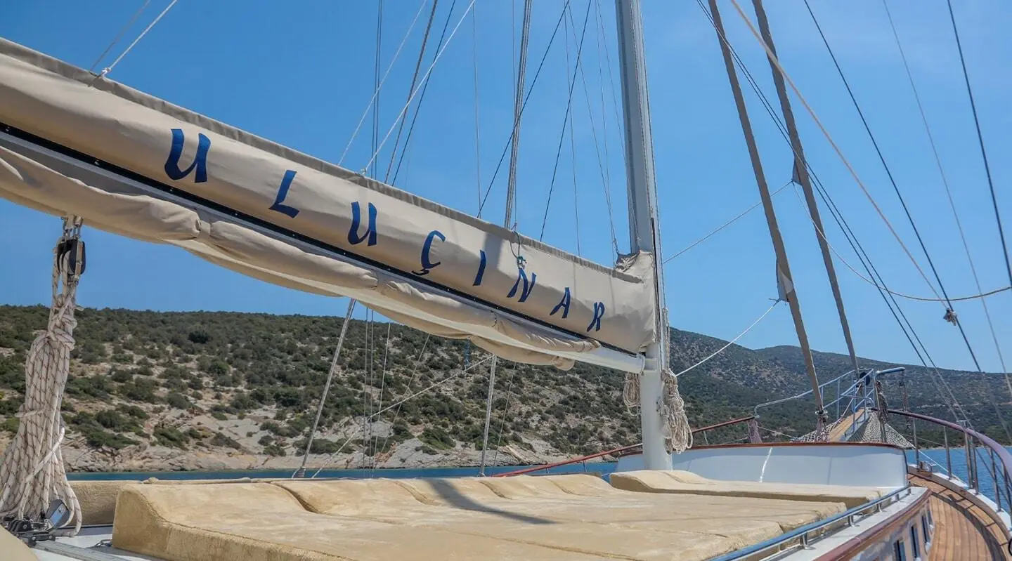 Ulucinar luxury gulet deck area with rigging and mountains in distance at sunset