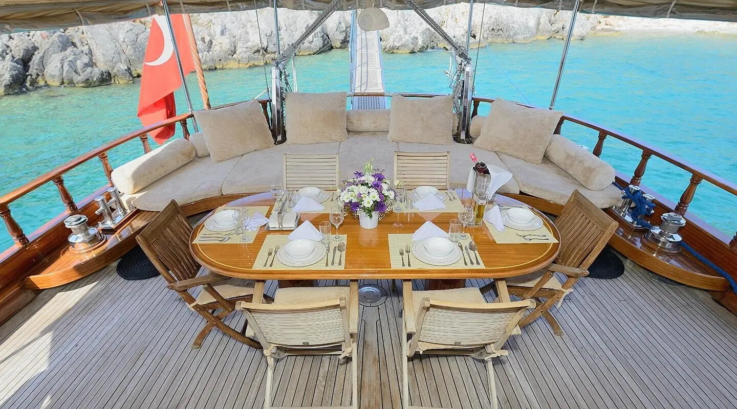 Aft deck seating with wooden table and cushions on Samarkand gulet, railings seen