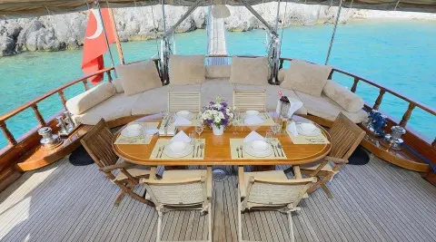 Aft deck seating with wooden table and cushions on Samarkand gulet, railings seen