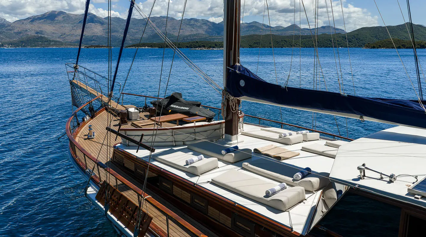 Eleganza yacht sun deck with lounge chairs and deck railing by the water