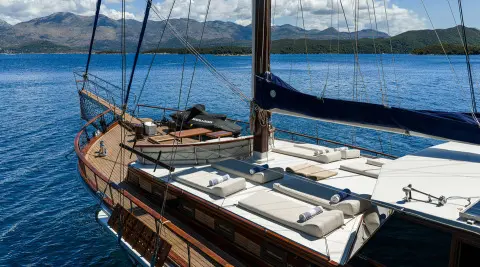 Eleganza yacht sun deck with lounge chairs and deck railing by the water