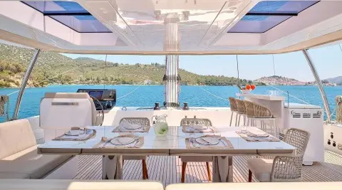 Genny luxury yacht dining area on deck with plates and glassware at sunset