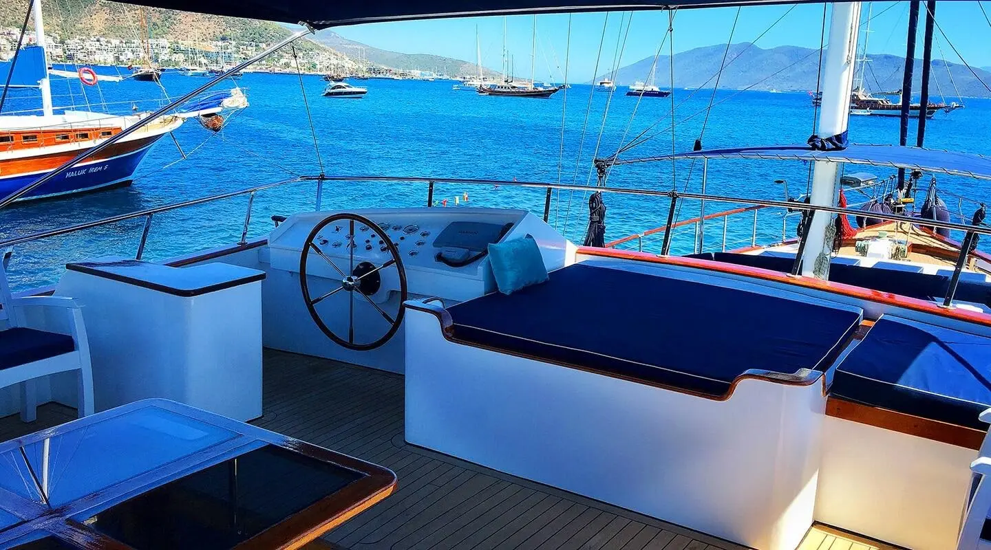 Maske 2 yacht deck with white loungers and blue sunshade near the water