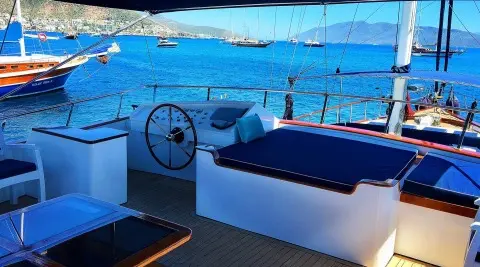 Maske 2 yacht deck with white loungers and blue sunshade near the water